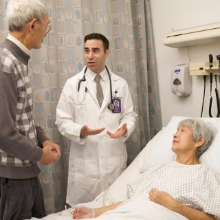 Family discussion with patient in bed and clinician speaking to husband. Photo credit: Hartford Foundation / Julie Turkewitz